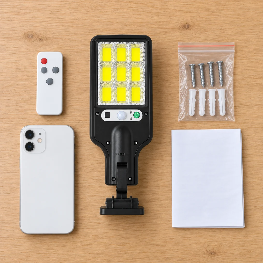 What's in the box: the compact solar street light beside a smartphone for size, the remote control, and mounting screws and anchors